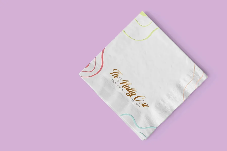 A paper napkin with The Nutty Cow logo and pastel lines