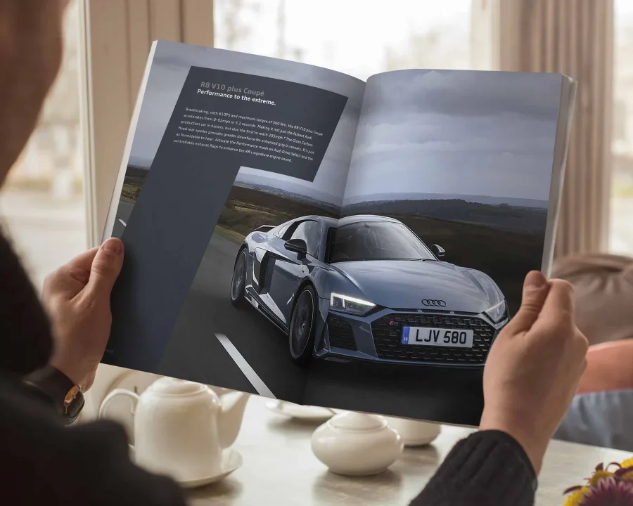 A reader holding the R8 V10 plus Coupé spread