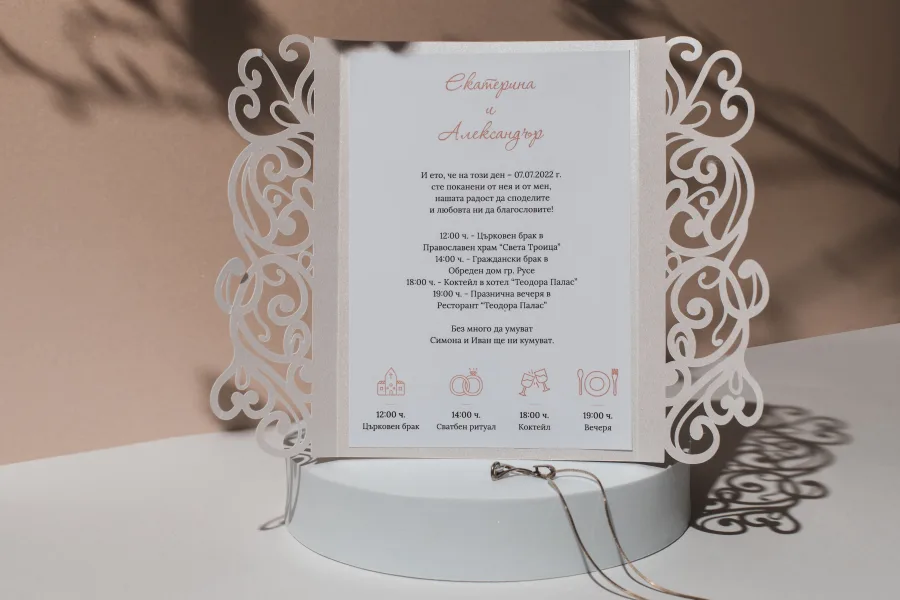 A gatefold wedding invitation with lace wings and a programme of the day with icons