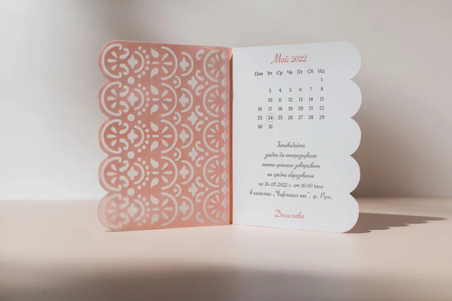 A folded invitation with a cut-paper cover and a calendar with the date circled