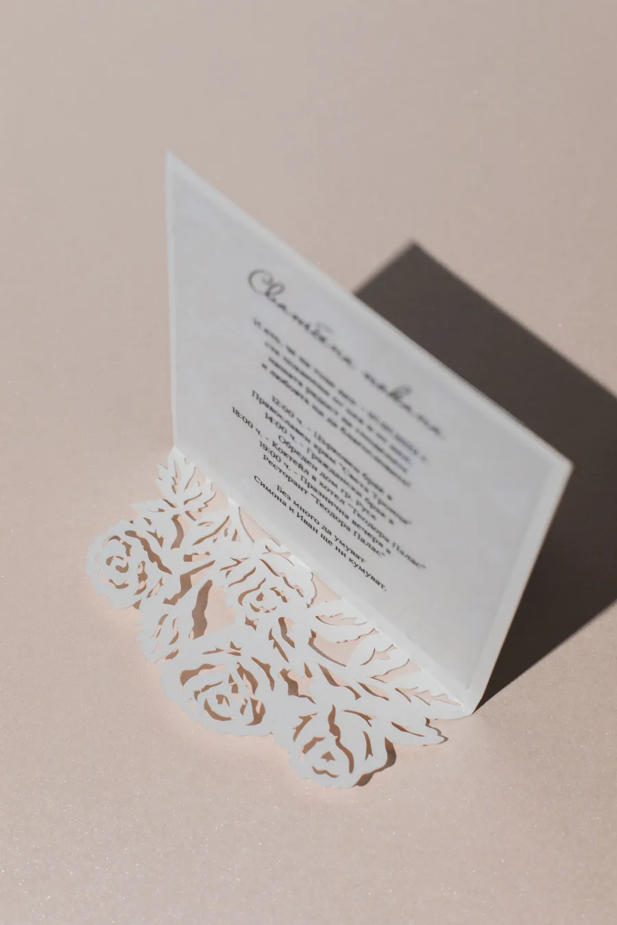 A vellum invitation on a base of cut-paper roses