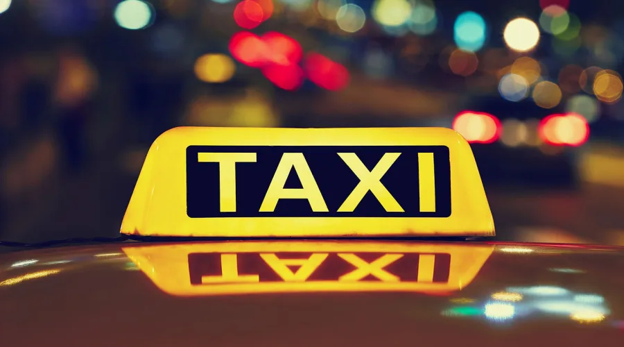 Светеща табела „TAXI“ на покрива на автомобил